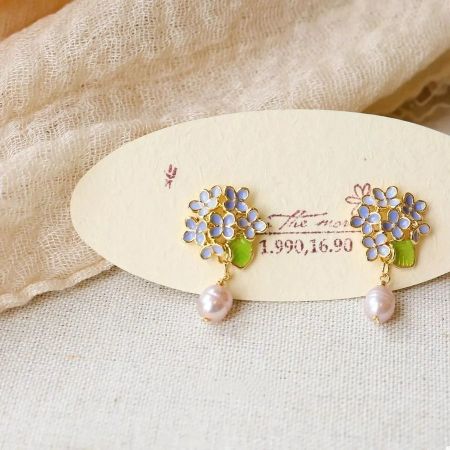 Floral pearl drop earrings with light blue flowers and pink pearls.
