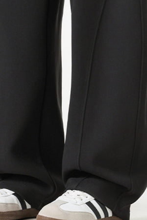 Black relaxed wide-leg sweatpants with drawstring detail and athletic shoes.
