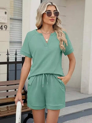 Green relaxed two-piece set with drawstring shorts and V-neck top with pockets.