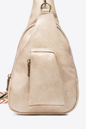 Beige textured sling bag with woven strap detail and front zip pocket