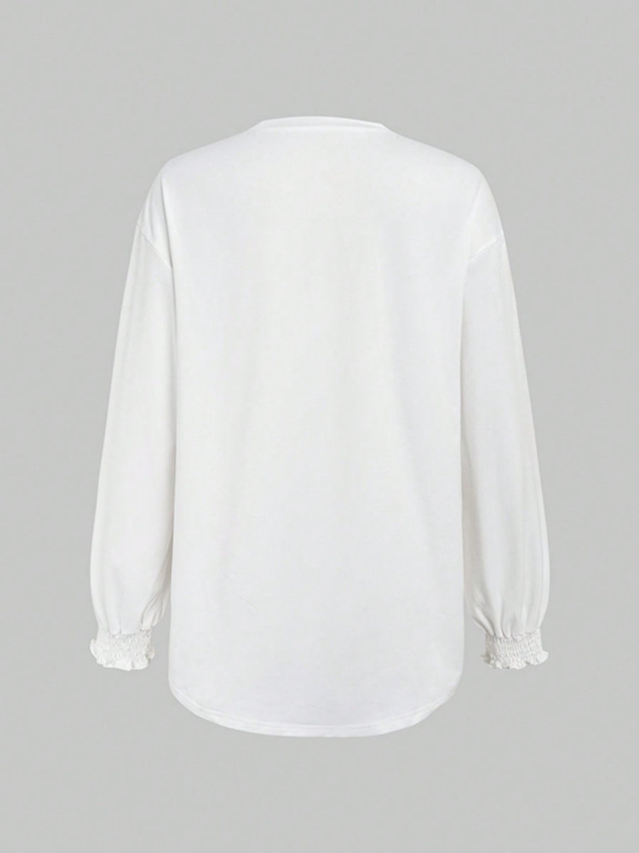 White oversized tunic top with ruffled cuffs and long sleeves.