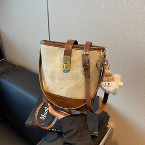 Vintage bucket crossbody bag in tan canvas with brown trim and a cute charm.