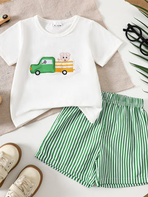 White baby tee with embroidered tractor and pig, green striped shorts.