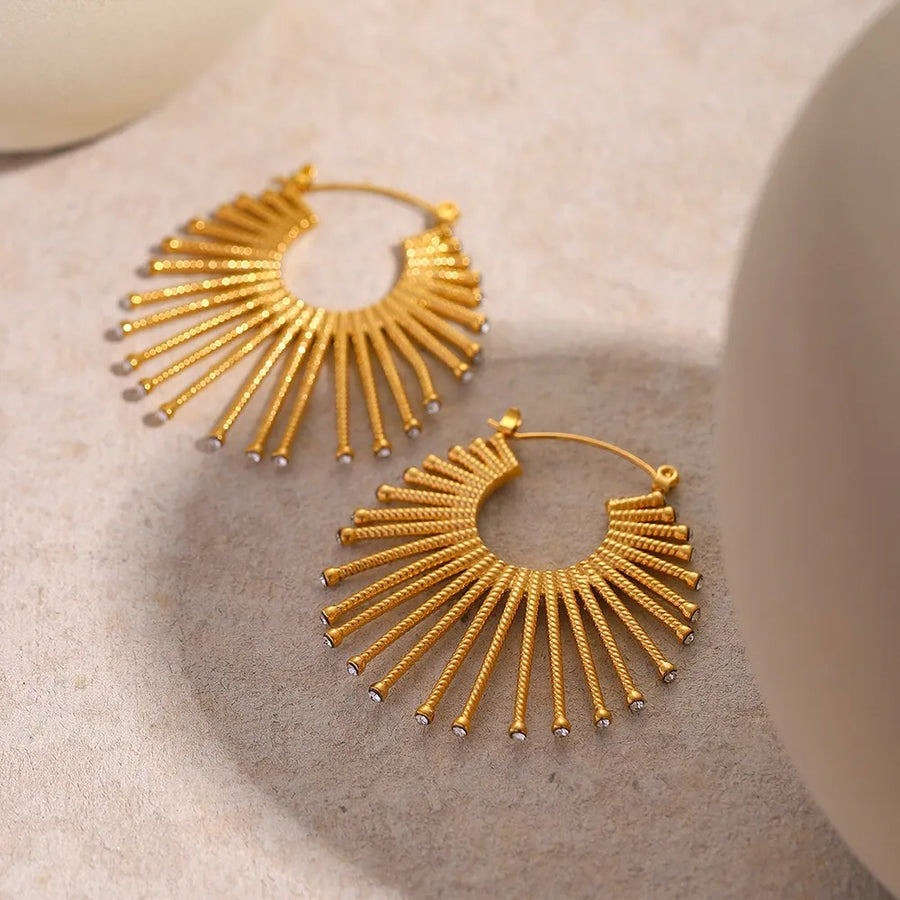 Gold earrings featuring zircon accents and sunburst
