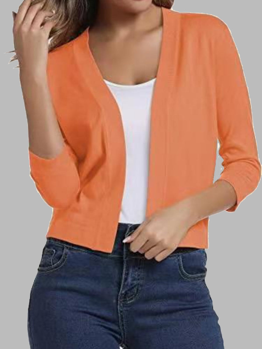 Cropped orange knit cardigan with elbow sleeves and open front, worn over a white top.