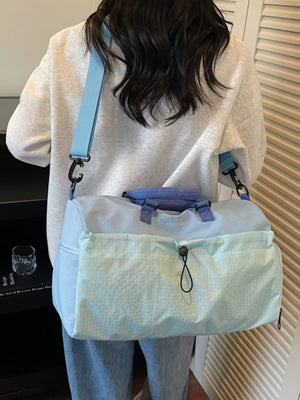 Chic two-tone nylon travel bag with aqua front pocket and detachable strap.