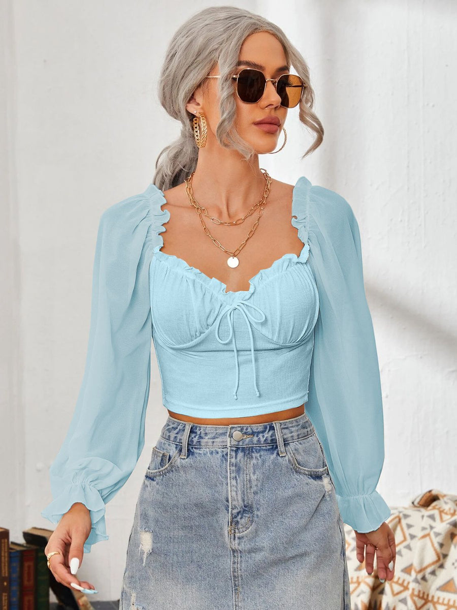 Pastel blue bustier blouse with tie front and sheer puff sleeves.