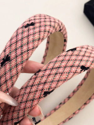 Pink tweed headband with black bow details and a plaid pattern