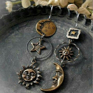 Cosmic asymmetry drop earrings in copper feature sun, moon, and star charms with mixed metal details.