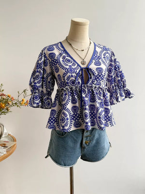 Chic floral tie-front blouse with 3/4 sleeves and ruffled cuffs, paired with denim shorts.