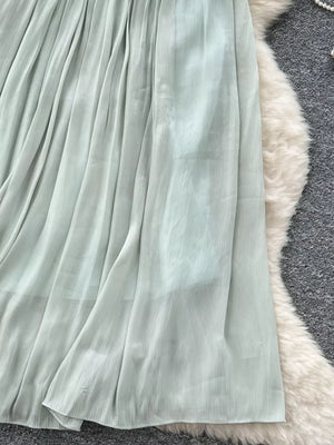 Light green pleated maxi skirt with a flowy, sheer fabric.