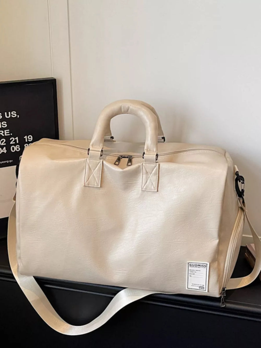 Off-white pu leather travel duffel bag with top handles and adjustable shoulder strap.
