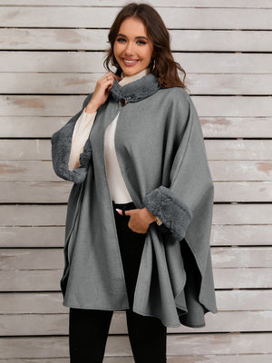 Gray faux fur trimmed cape coat with a gold clasp closure and wide sleeves.