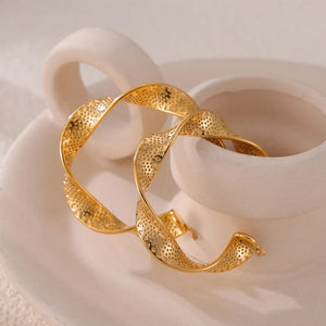 Textured gold hoop earrings with a twisted spiral design and perforated pattern.