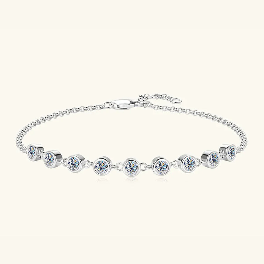 Silver bezel-set moissanite tennis bracelet with a delicate chain and clasp.