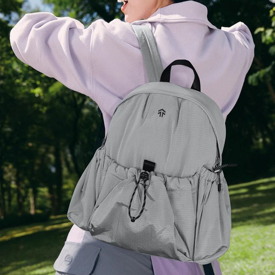 Gray lightweight nylon drawstring backpack with front cinched pockets and a small logo detail.