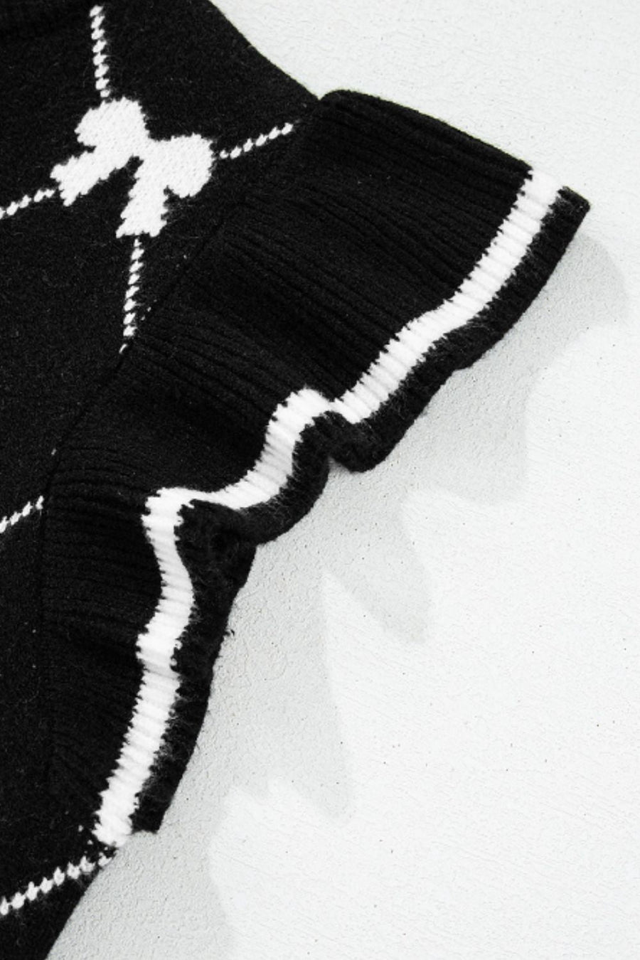 Black knit vest with white diamond bow pattern and striped trim