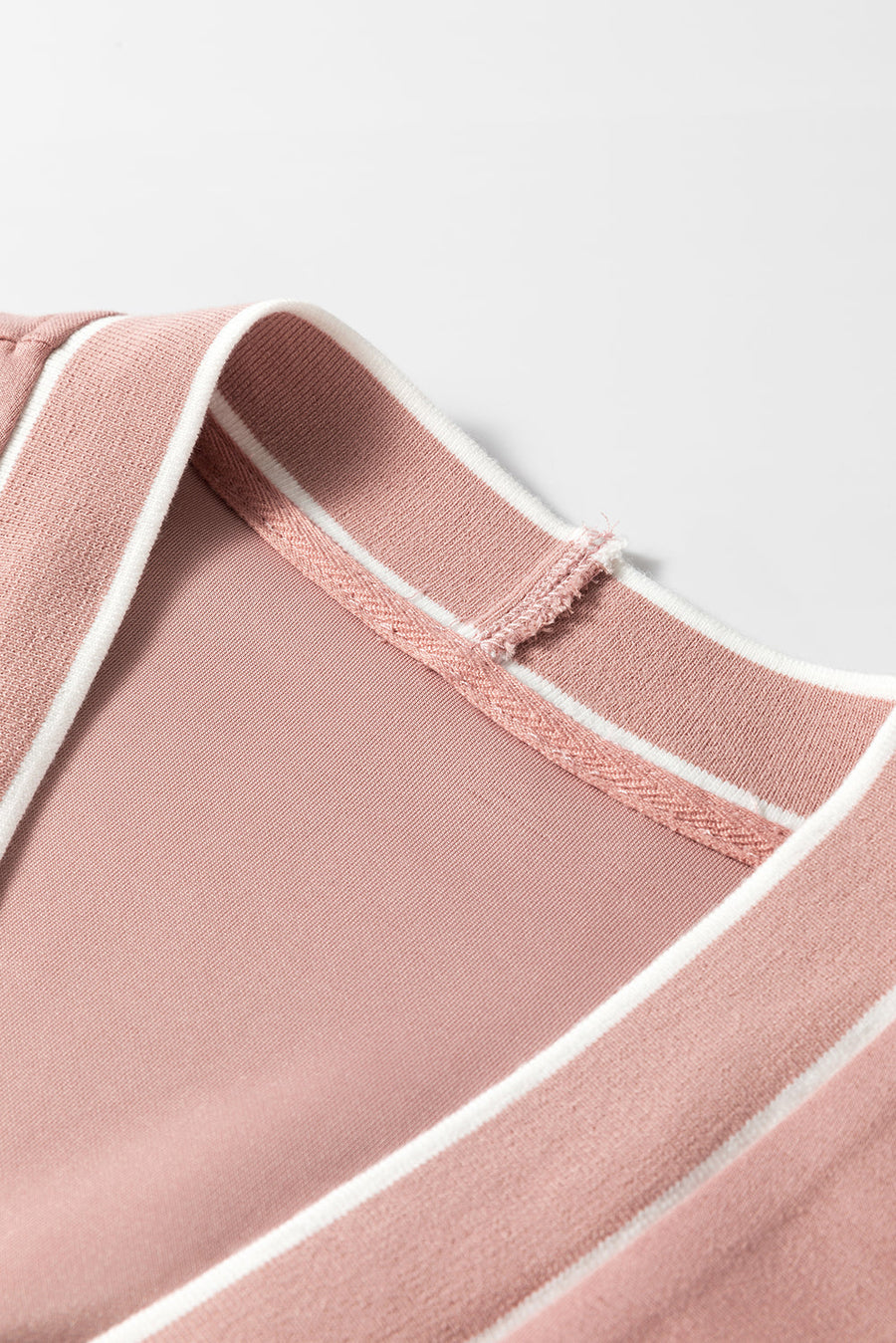 Dusty pink cardigan with white varsity trim detail at the neckline.