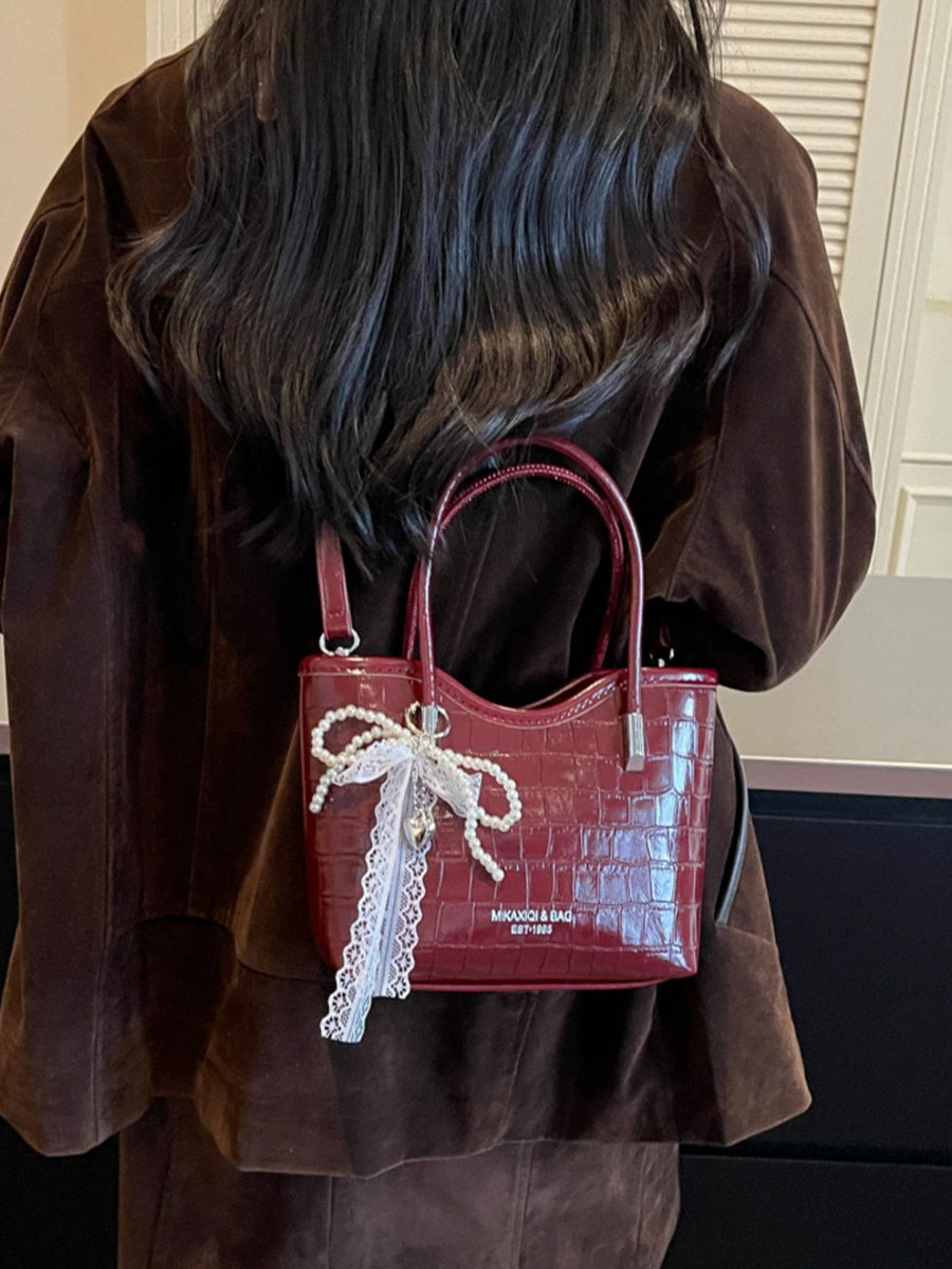 Off-white crossbody bag featuring top handle and animal-print