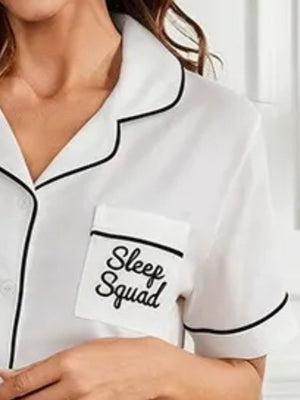 White pajama top with black trim and "Sleep Squad" embroidered pocket