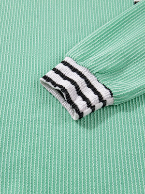 Turquoise long-sleeve top with twisted ribbed texture and striped cuffs.