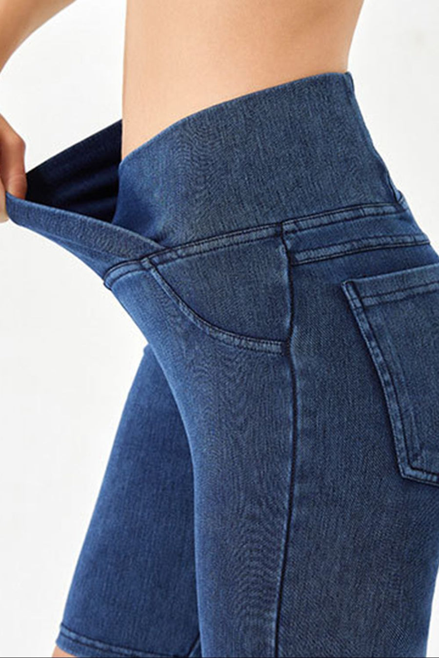 Medium wash denim bermuda shorts with a high rise crisscross waistband and pocket details.