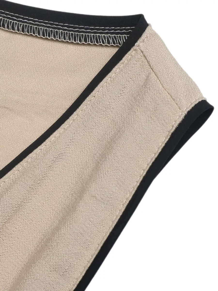 Elegant beige maxi dress detail with black piping and contrast stitching.