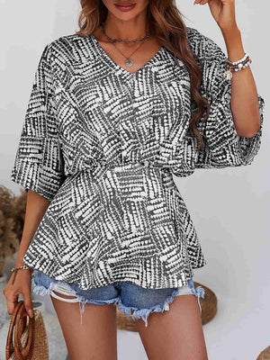 Abstract print cinched waist blouse with V-neck and short sleeves in black and white.
