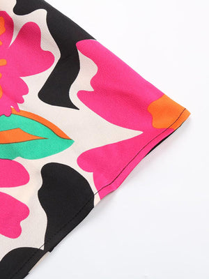 Vibrant floral midi dress with spaghetti straps in black, pink, orange, and green abstract print.