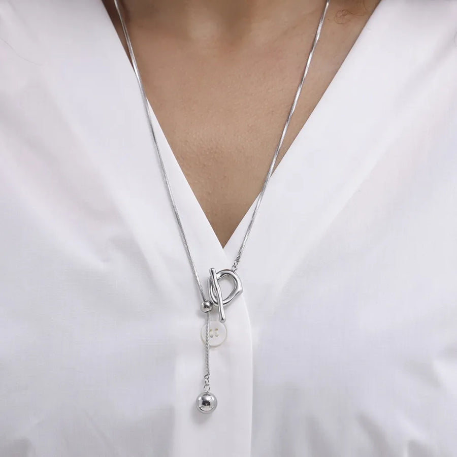 Silver lariat necklace with toggle closure and dangling ball charm.