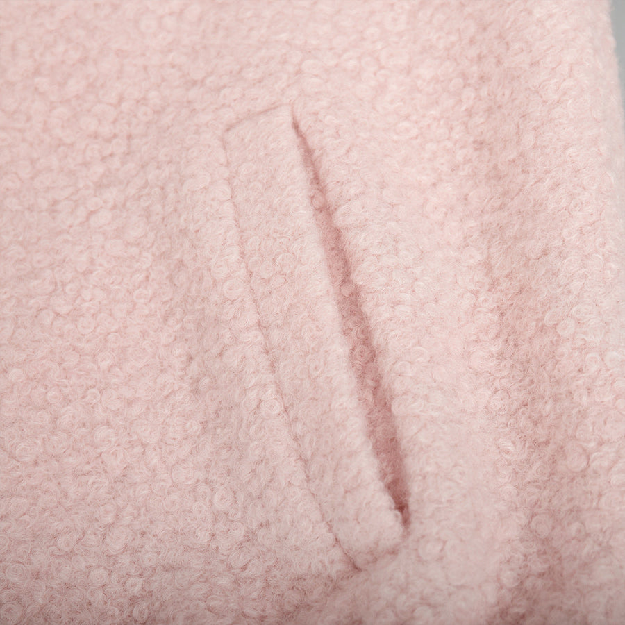 Blush pink textured bouclé bomber jacket with rounded neck and pocket detail.
