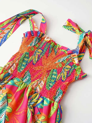 Tropical tie-strap smocked midi dress with vibrant leaf print and ruffled neckline.