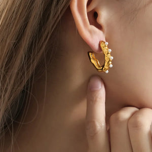 Sculpted gold hoop earrings with pearl accents, a textured design.