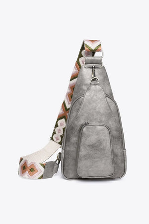 Mid gray PU sling bag with embroidered strap and front zip pocket.