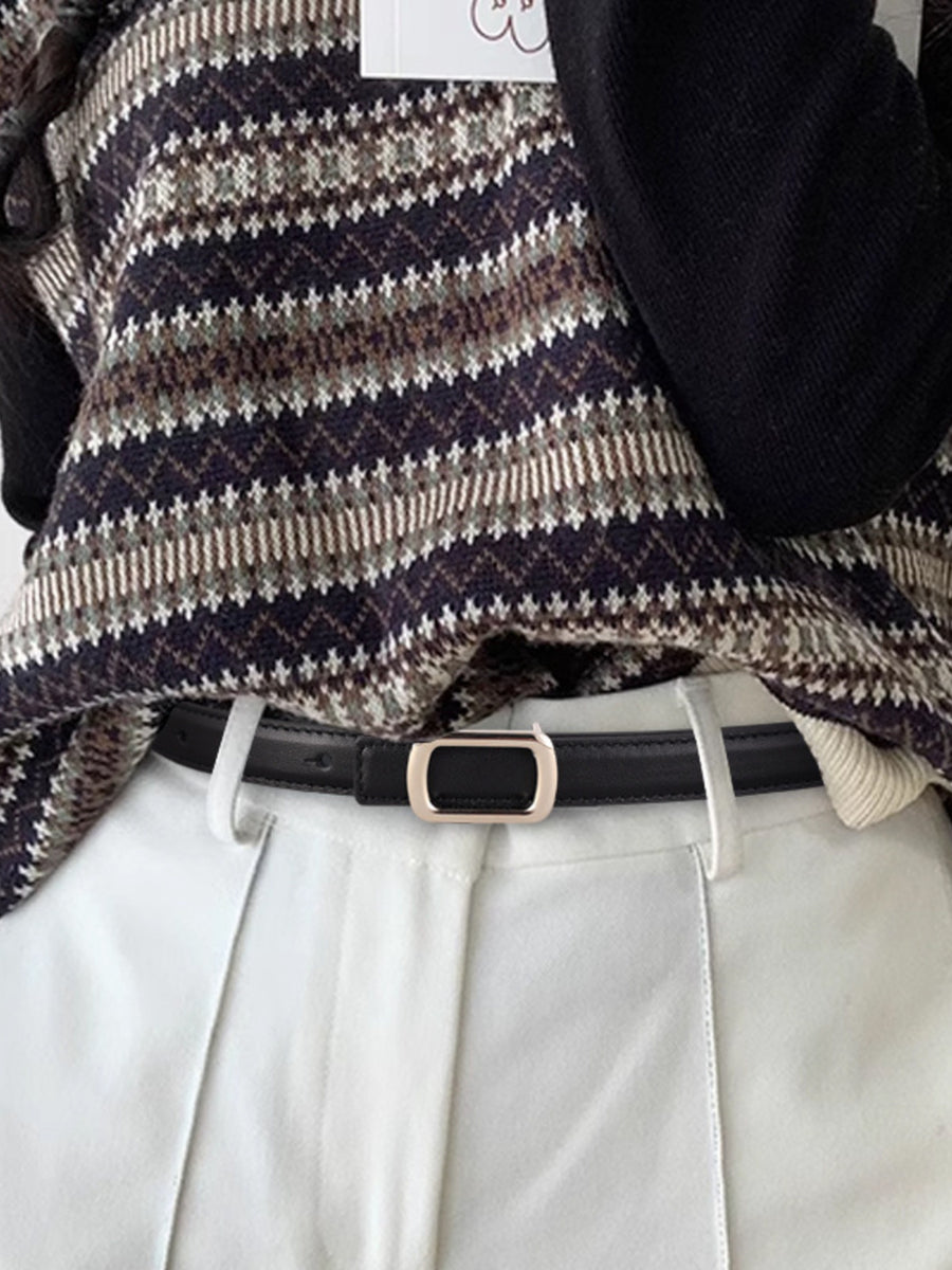 Black leather skinny belt with modern gold buckle, styled with white pants and a patterned sweater.