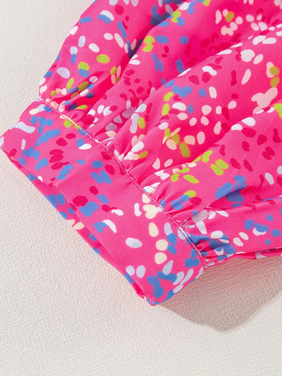 Hot pink blouse with a colorful abstract dot print and ruched mesh sleeves.
