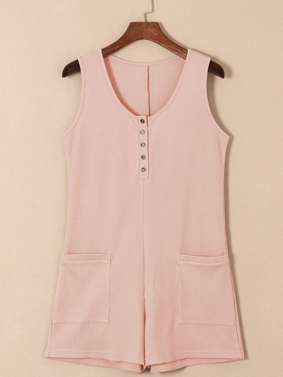 Blush pink waffle knit button-down romper with pockets and a scoop neckline.