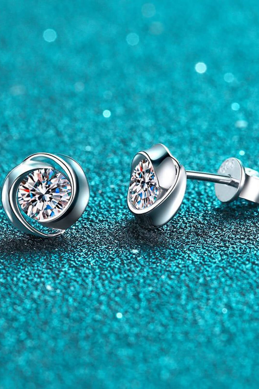 Silver halo crystal stud earrings with a swirling design.
