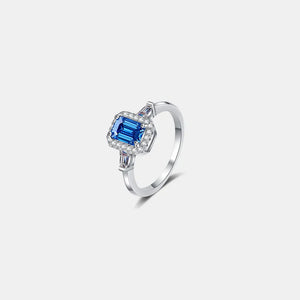 Emerald cut royal blue moissanite halo ring in sterling silver with baguette accents.