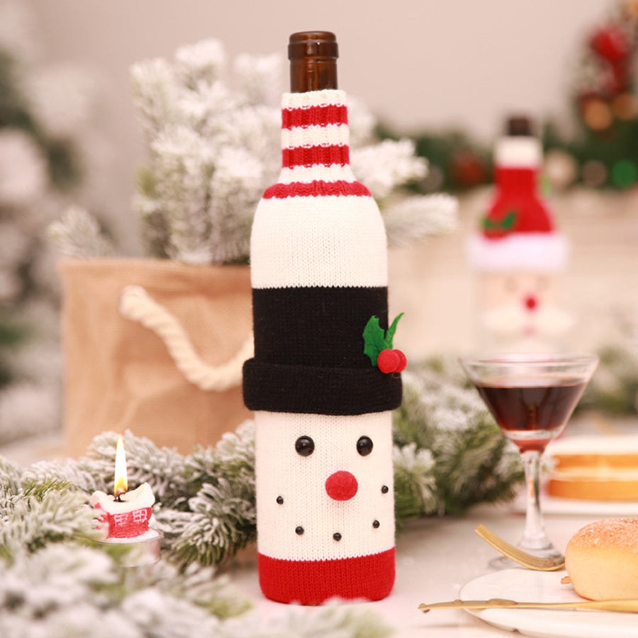Festive knit bottle cover with red and white stripes, black hat, and snowman face details.