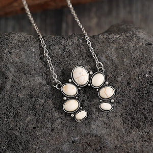 White horseshoe necklace with artificial turquoise stones and silver chain.