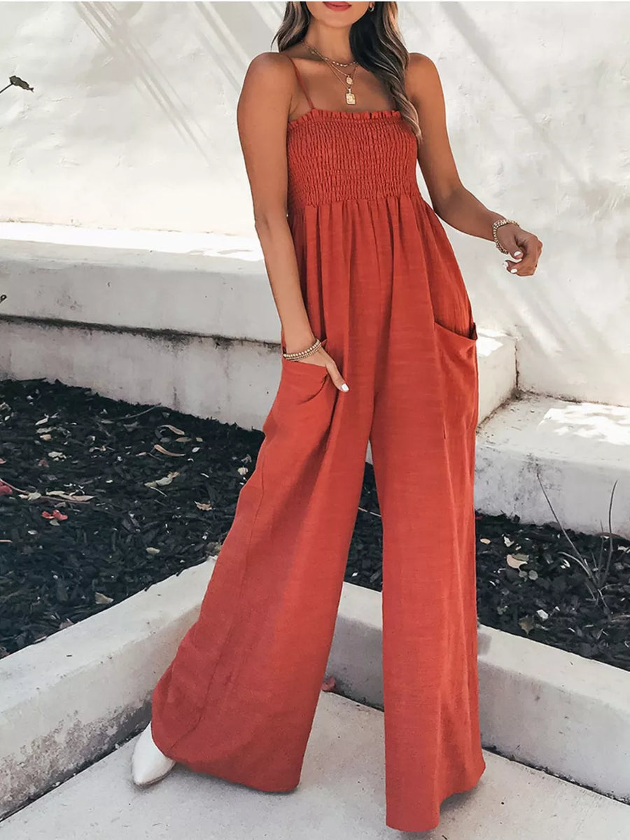 Orange-red smocked wide leg romper with pockets and spaghetti straps.