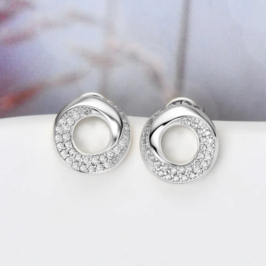 Silver pavé circle stud earrings with a twisted design and sparkling stones.