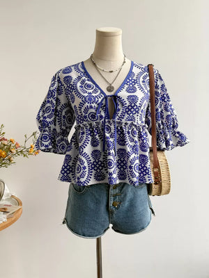 Chic floral tie-front blouse with 3/4 sleeves and ruffled cuffs, styled with denim shorts.