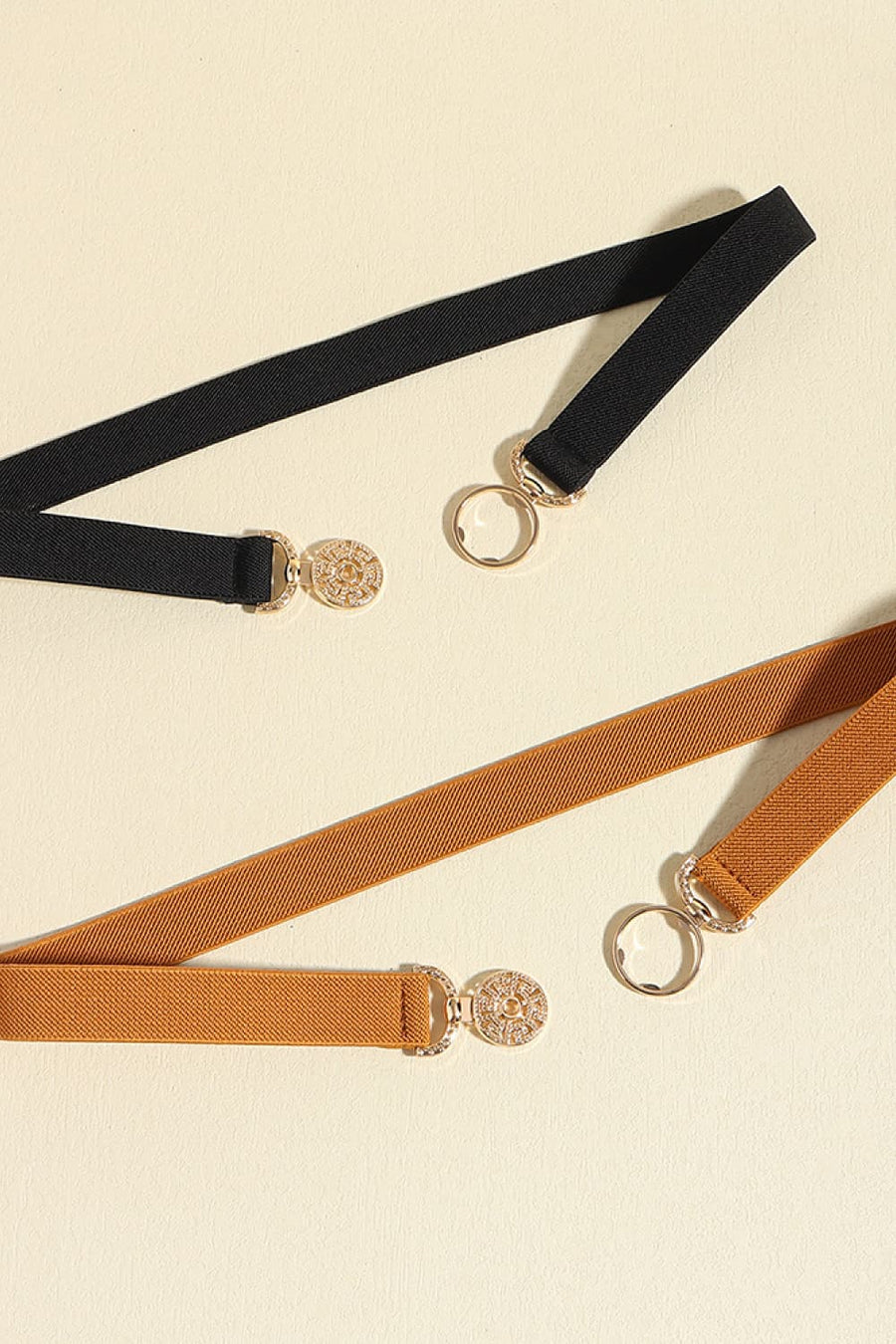 Elasticated belts in black and caramel with medallion buckle and gold ring detail