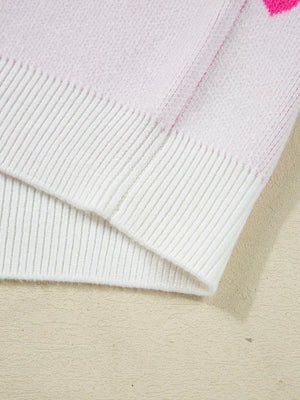 Pink and white knit sweater with heart pattern detail and ribbed trim.