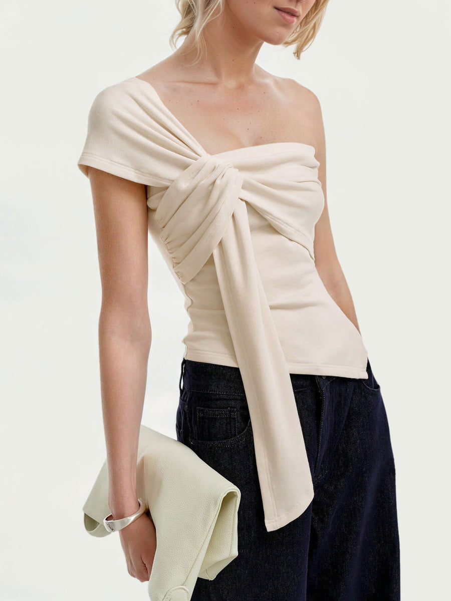 Beige asymmetrical t-shirt with knot detail and ruched sides, styled with dark denim.
