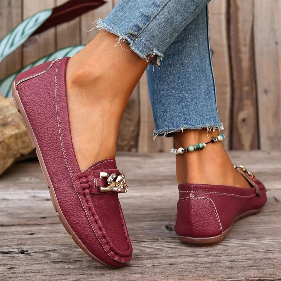 Burgundy round-toe loafers with gold chain detail and stitched trim.
