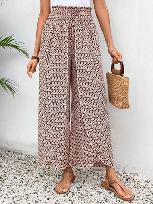Palazzo pants with a geometric floral print in blush pink and black, featuring a wrap-front and wide legs.