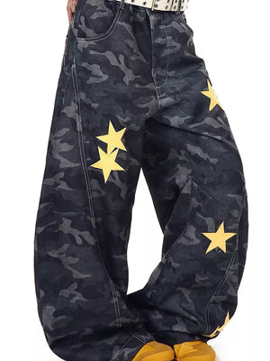 Men's baggy jeans in dark camo print with yellow star embellishments and white stitching.